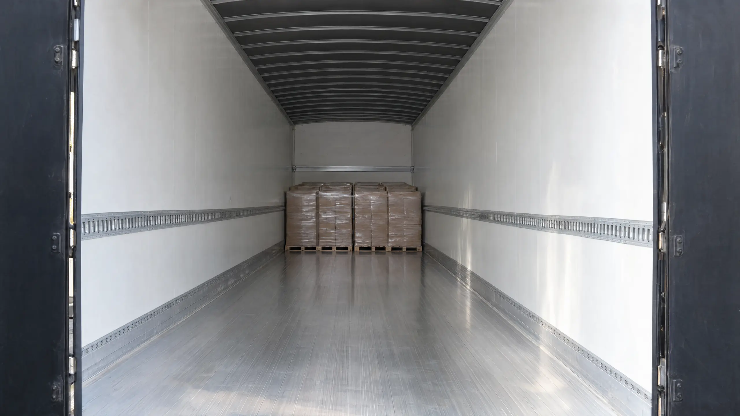 Inside a dry van: a group of wrapped pallets at the front wall and open floor back to the rear doors