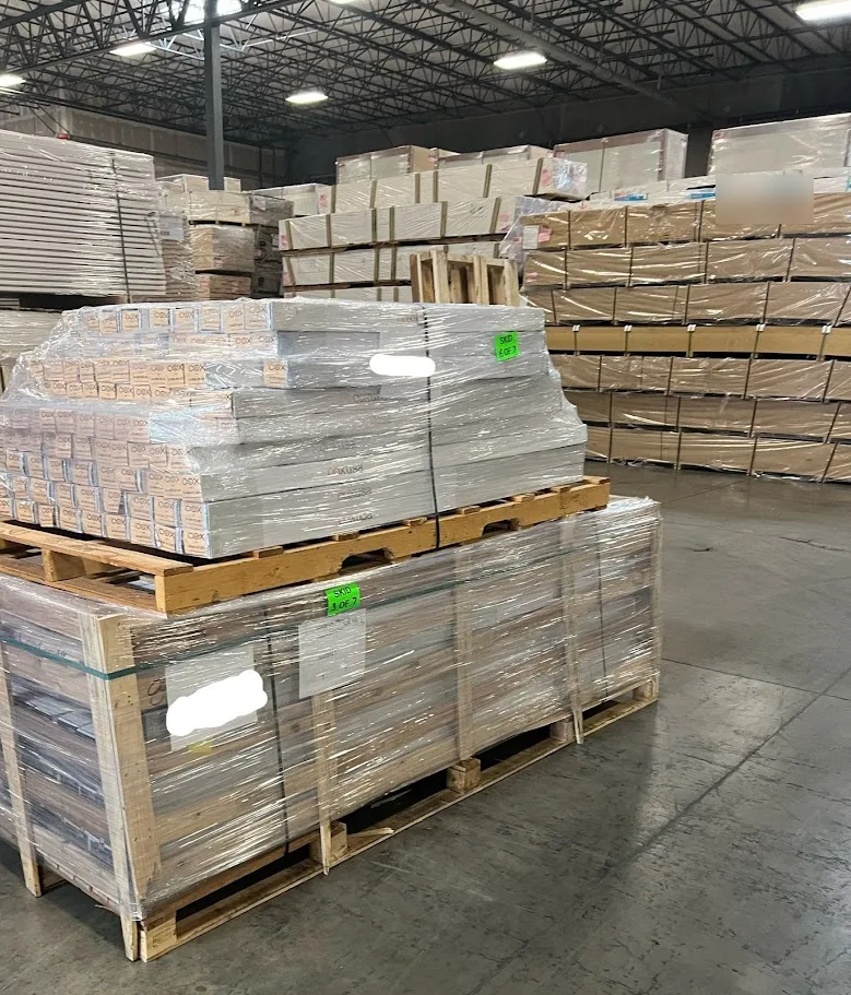 Wrapped, skid-tagged pallets staged under deep steel racking inside a partner warehouse